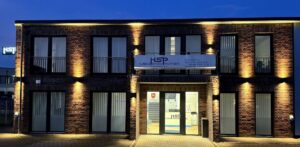 Ein modernes Backsteingebäude mit Beleuchtung und einem großen Schild mit der Aufschrift „Hüsing Stark Partner Rechtsanwälte & Notar“.